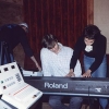 Carolyne showing Joe Terry a piano part.  With her hands busy, she puts money for a food delivery in her mouth!